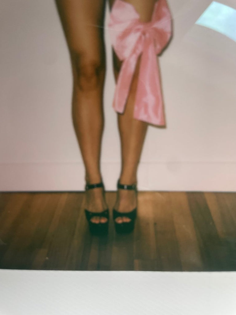 Large pink silk shantung bow accessory with elastic ties styled around the thigh