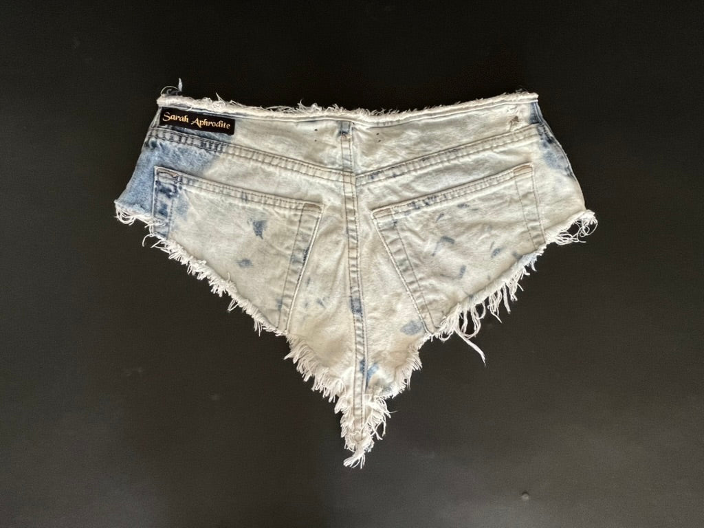 Denim shorts with frayed edges on a black background