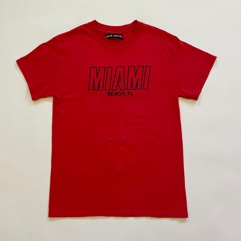 Red repurposed T-shirt with heart cut-out and Miami Beach Florida embroidery, displayed flat on the floor