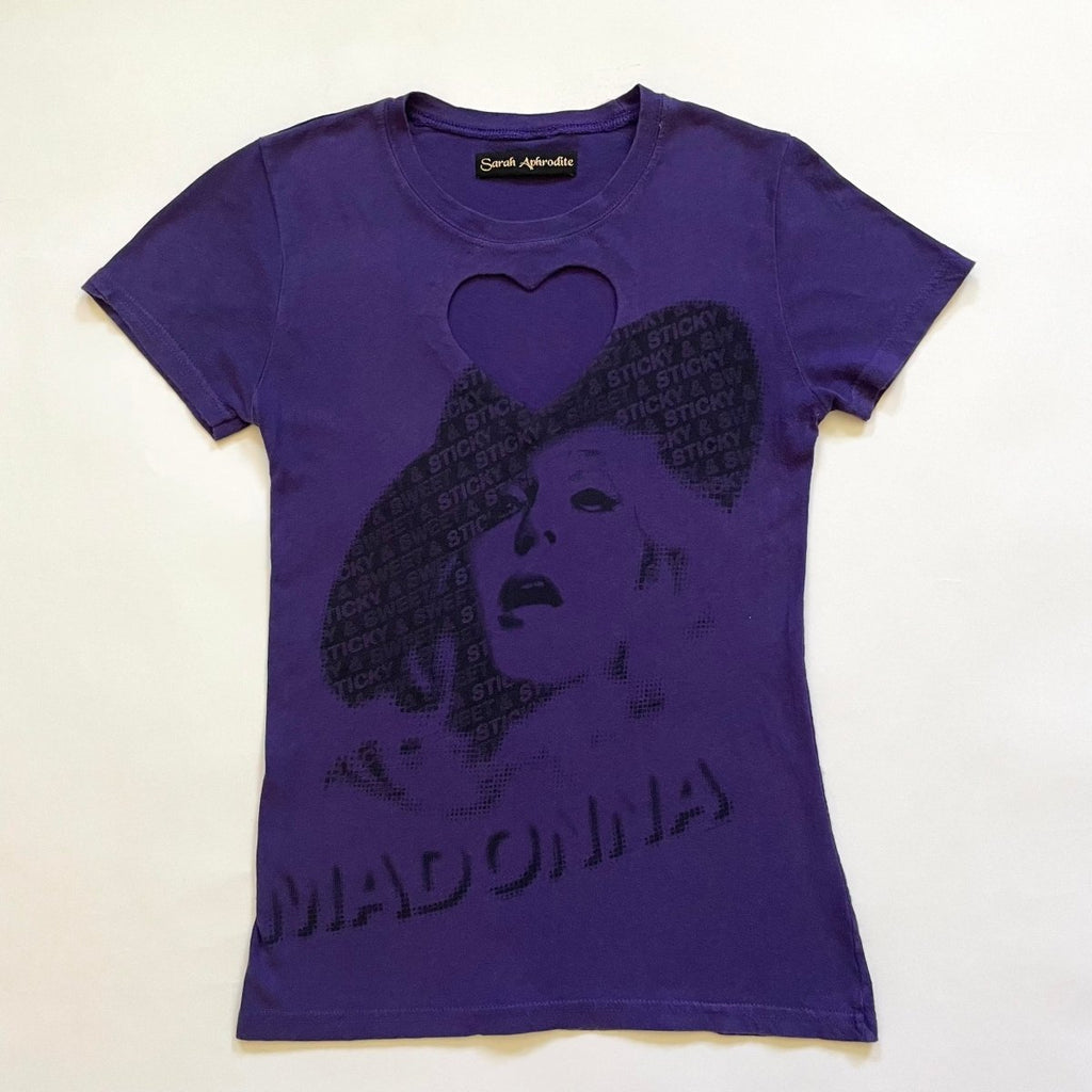 A purple t-shirt with a heart cut-out design and a printed image of a woman's face in the center displayed flat on the floor on a white background