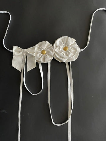 Handmade white flower and bow accessory with gold button centers and long straps by Sarah Aphrodite, made from upcycled fabric scraps, worn as belt or top