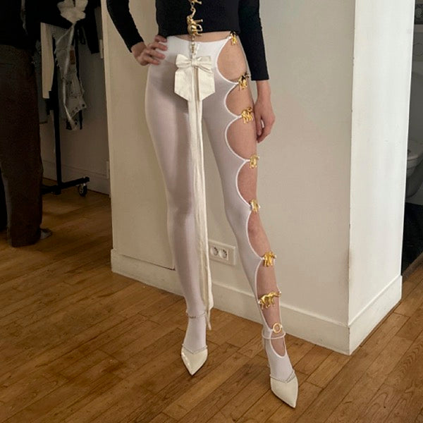 Handmade white opaque tights with seven reused gold elephant buckles along the left leg by Sarah Aphrodite, limited-edition upcycled fashion piece