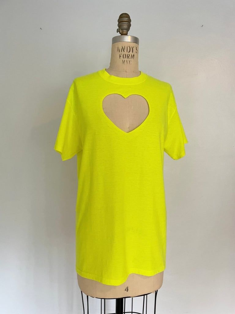 Oversized neon yellow t-shirt with a heart cut-out on the chest, displayed on an XS mannequin against a white background.