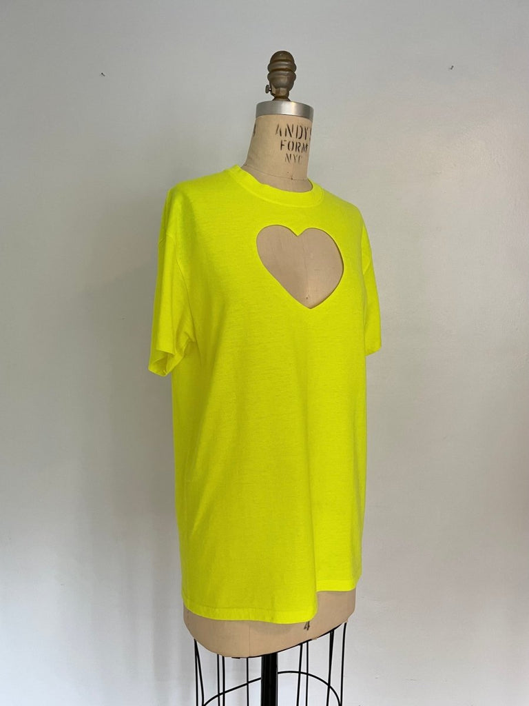 Oversized neon yellow t-shirt with a heart cut-out on the chest, displayed on an XS mannequin against a white background.