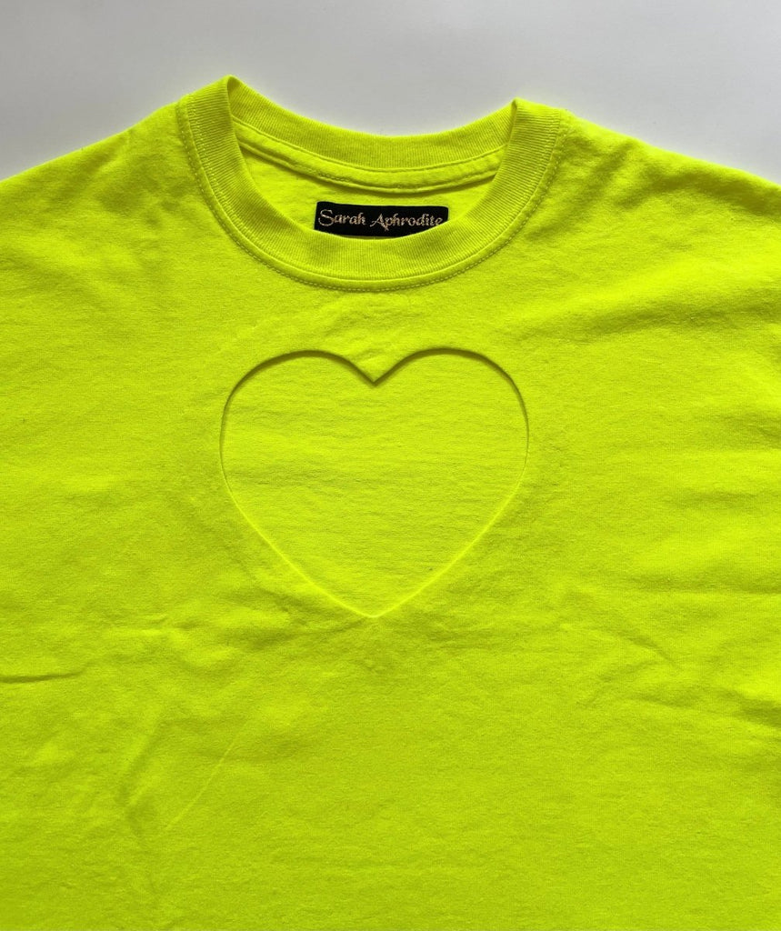 detail of a heart cut out on an oversized neon yellow t-shirt with a heart cut-out on the chest, displayed flat on a white background.
