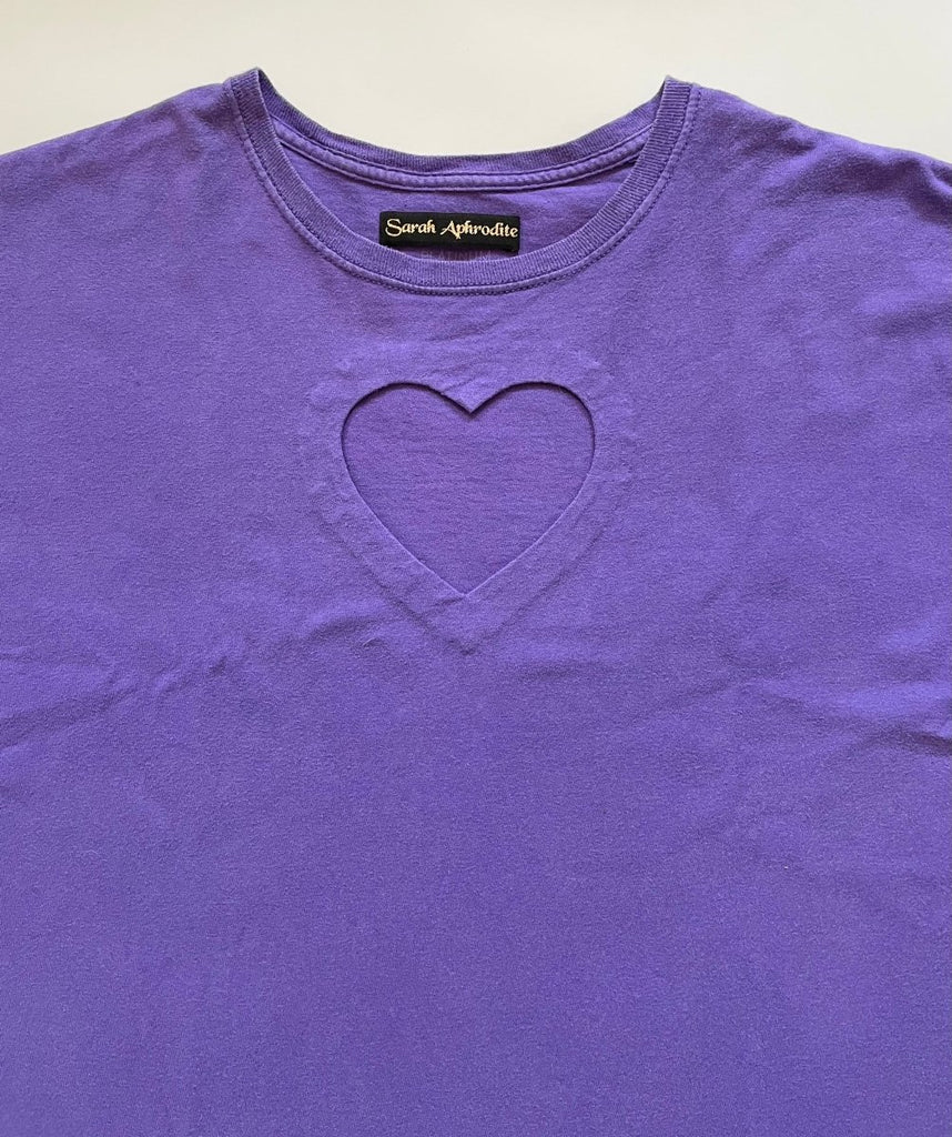 close-up of a heart cut-out in an oversized purple t-shirt , displayed flat on the floor