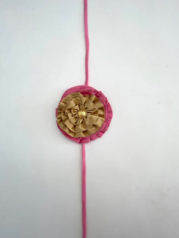 Handmade pink and gold double fabric flower accessory with gold button center, shown with elastic ties for wearing on ankle or shoulder.