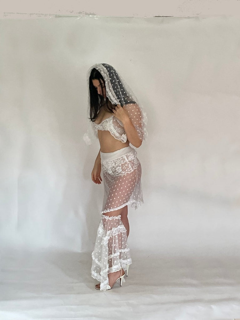 Woman wearing a white lace outfit against a plain background