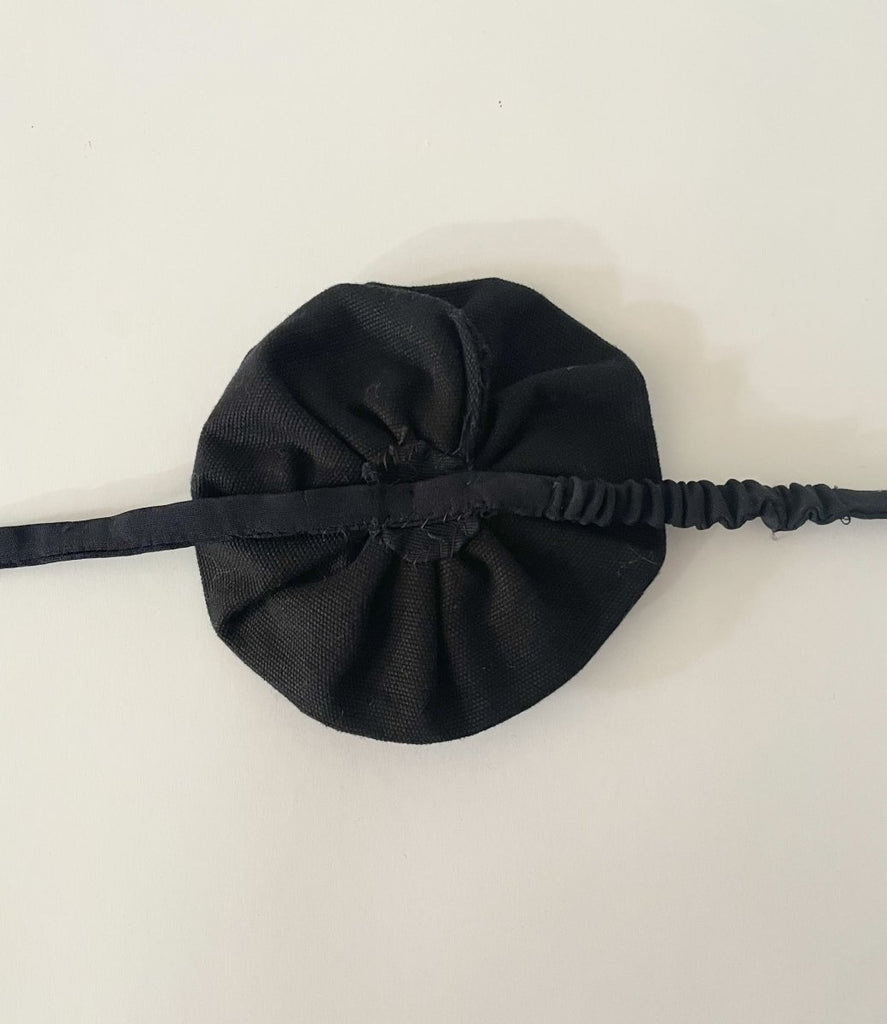 One-of-a-kind sustainable black flower accessory by Sarah Aphrodite. Gold button center with elastic tie, handmade from upcycled canvas scrap. 4-inch size.