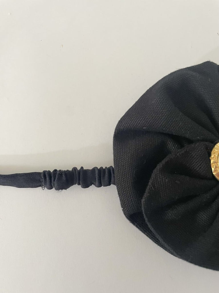 One-of-a-kind sustainable black flower accessory by Sarah Aphrodite. Gold button center with elastic tie, handmade from upcycled canvas scrap. 4-inch size.