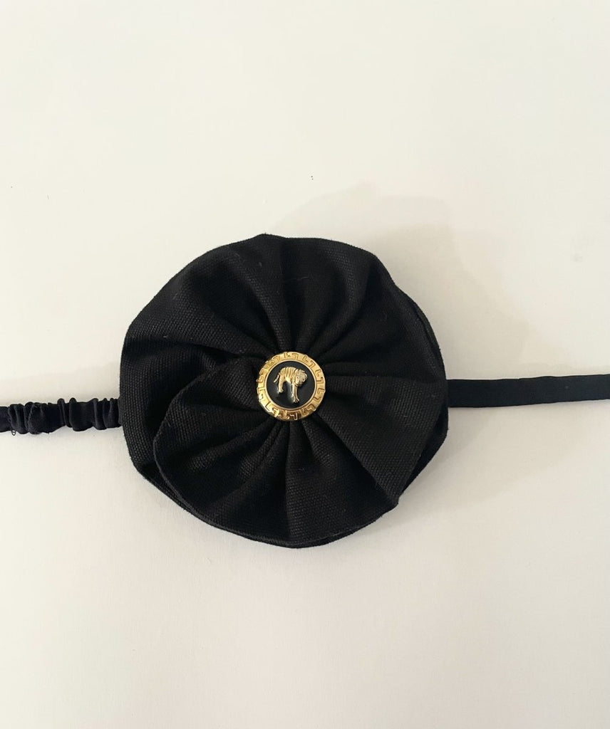 One-of-a-kind sustainable black flower accessory by Sarah Aphrodite. Gold button center with elastic tie, handmade from upcycled canvas scrap. 4-inch size.