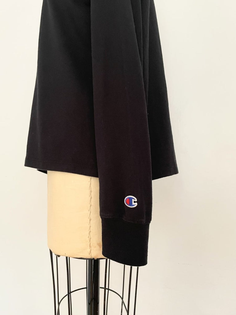 One-of-a-kind sustainable black long sleeve heart cut-out top by Sarah Aphrodite. Handmade from repurposed cotton with Champion logo on sleeve.