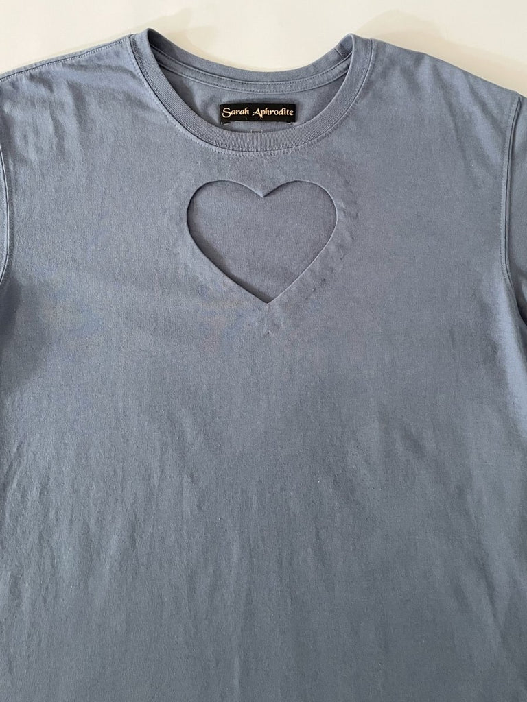 One-of-a-kind sustainable greyish blue t-shirt by Sarah Aphrodite. Large heart cut-out on chest, Eddie Bauer logo on bottom left with paint stain. Fits XS–Large.