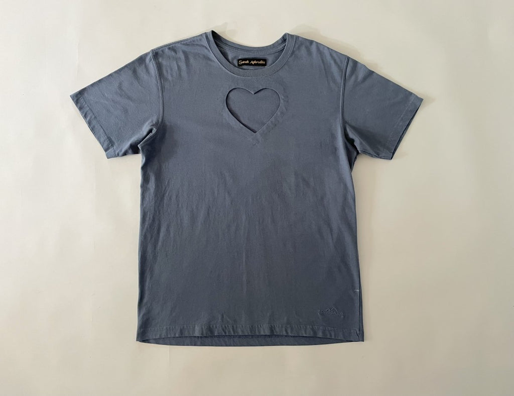 One-of-a-kind sustainable greyish blue t-shirt by Sarah Aphrodite. Large heart cut-out on chest, Eddie Bauer logo on bottom left with paint stain. Fits XS–Large.