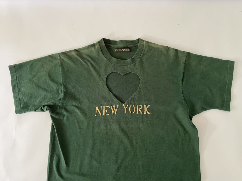 One-of-a-kind sustainable heart cut-out t-shirt dress by Sarah Aphrodite, handmade from repurposed t-shirts. Features yellow “NEW YORK” embroidery, natural fading marks, and fits Medium.