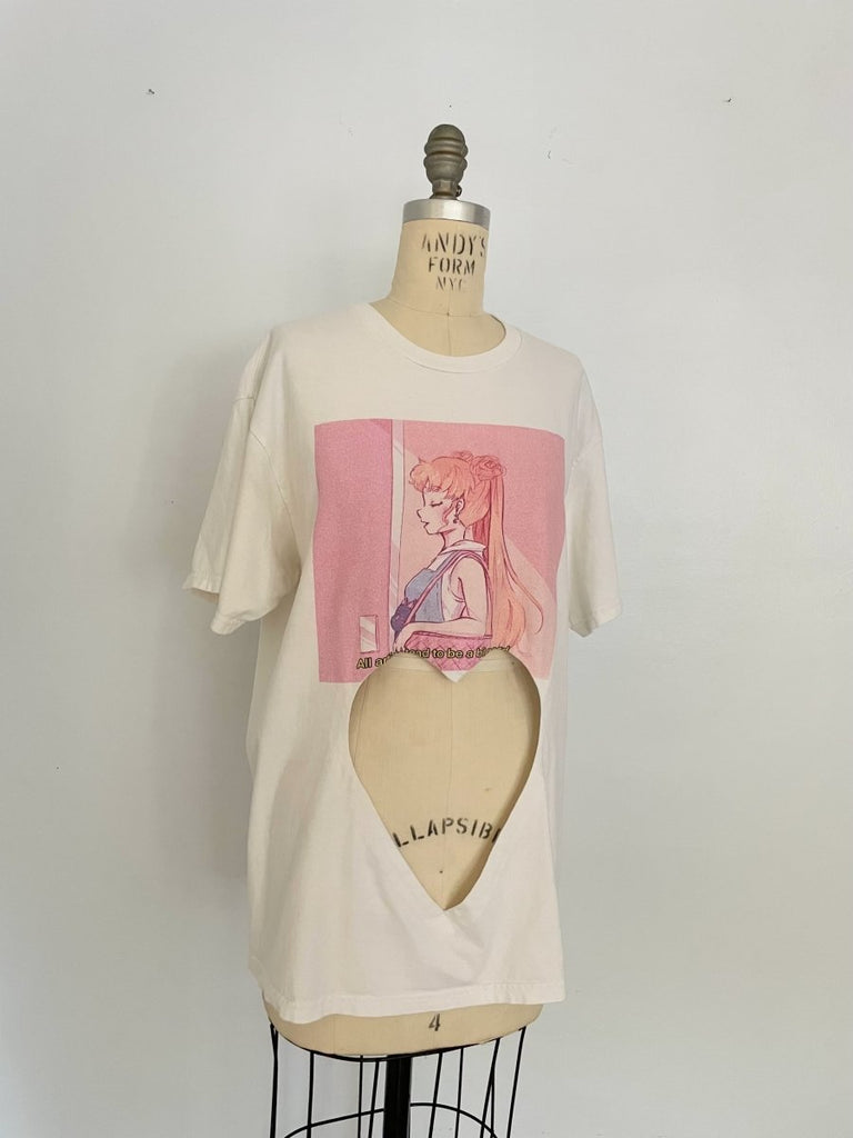 One-of-a-kind sustainable t-shirt by Sarah Aphrodite, featuring a belly heart cut-out and pink artist “girl” print. Made from repurposed cotton, fits Medium–Large.