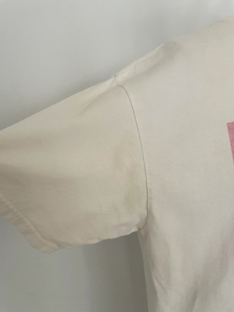 One-of-a-kind sustainable t-shirt by Sarah Aphrodite, featuring a belly heart cut-out and pink artist “girl” print. Made from repurposed cotton, fits Medium–Large.