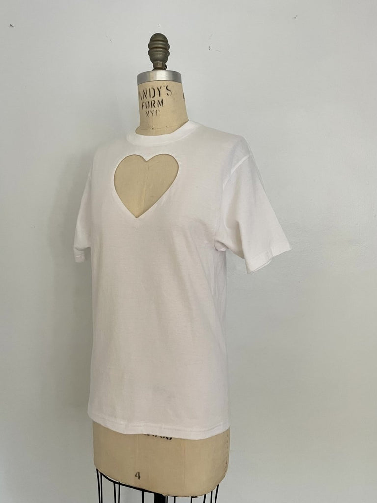One-of-a-kind sustainable white t-shirt by Sarah Aphrodite, featuring a large heart cut-out. Handmade from repurposed fabric. Fits S–M, eco-conscious design.