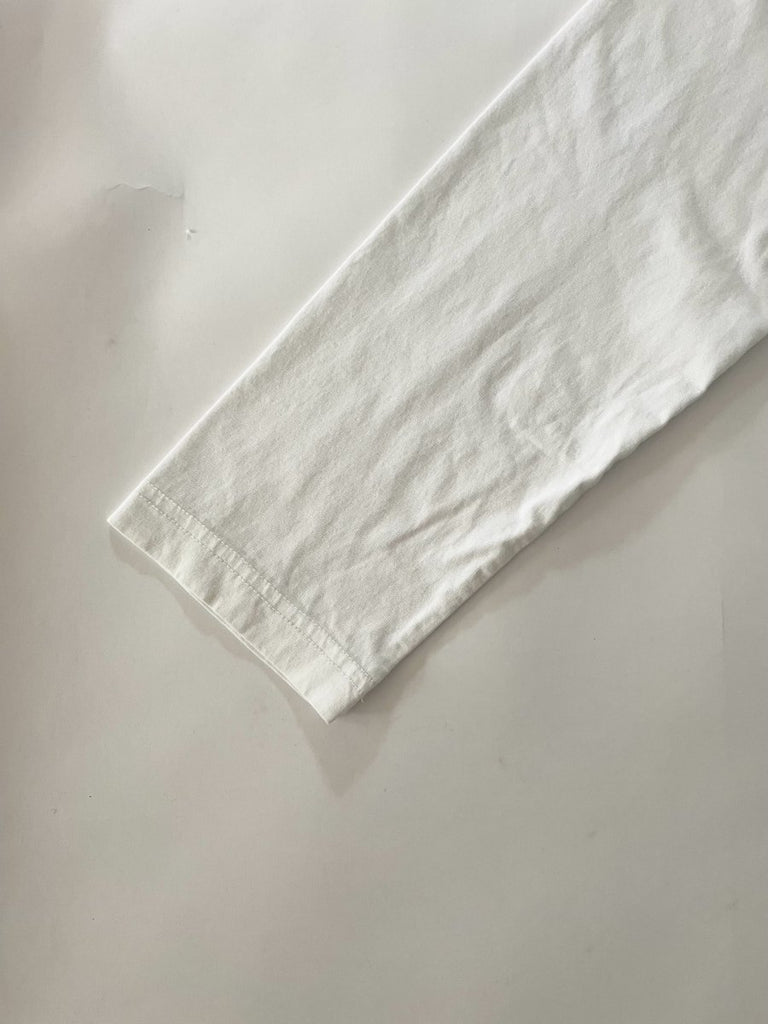 One-of-a-kind sustainable white long sleeve top by Sarah Aphrodite. Features heart cut-out on chest, handmade from repurposed cotton. Fits size Medium.