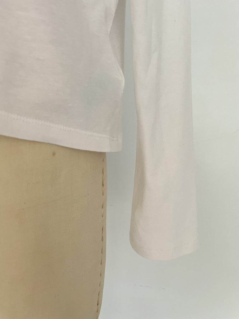 One-of-a-kind sustainable white long sleeve top by Sarah Aphrodite. Features heart cut-out on chest, handmade from repurposed cotton. Fits size Medium.