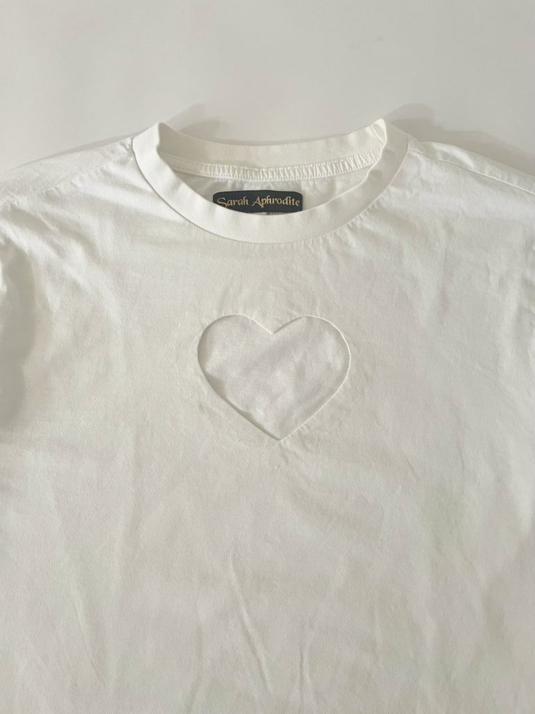 One-of-a-kind sustainable white long sleeve top by Sarah Aphrodite. Heart cut-out on chest, slightly longer length, handmade from repurposed cotton. Fits Medium.