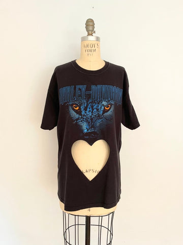 A black t-shirt with a blue cat eye print and a heart cut out on the belly area, displayed on a mannequin.