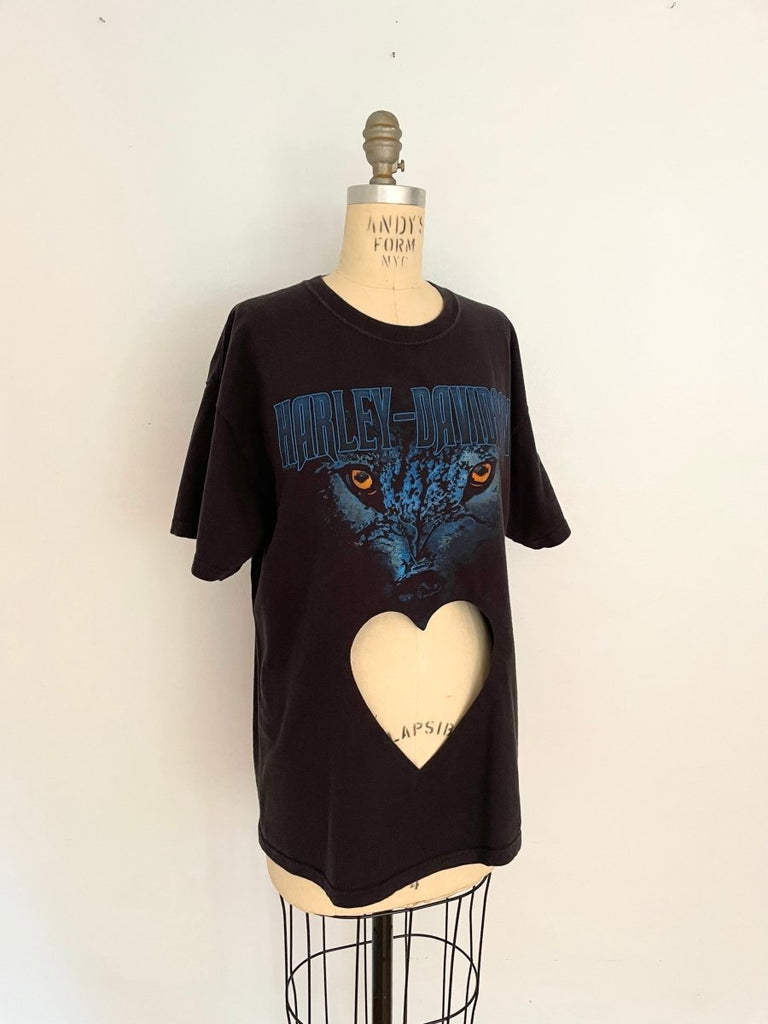 A black t-shirt with a blue cat eye print and a heart cut out on the belly area, displayed on a mannequin.