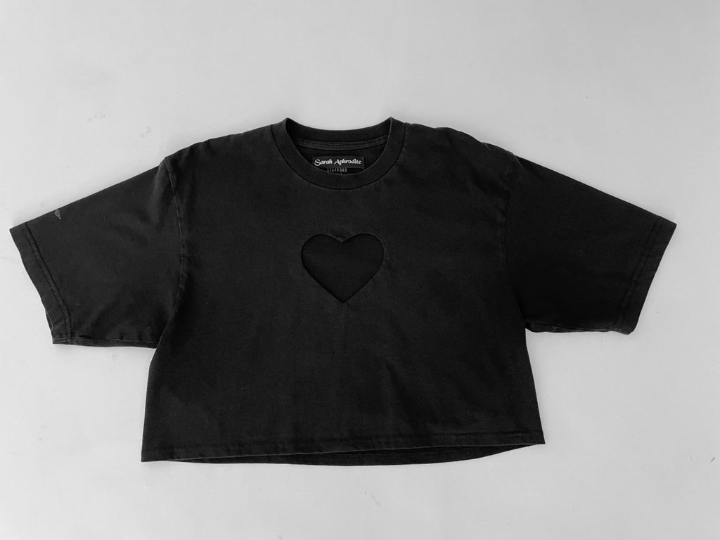 handmade black cropped T-shirt with a hart cut out on the chest displayed flat on the floor made from a recycled black tshirt