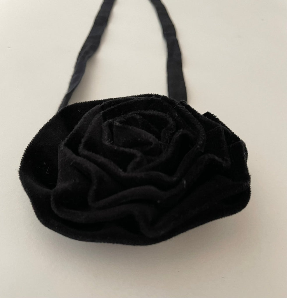black velvet flower accessory with ties on a white background