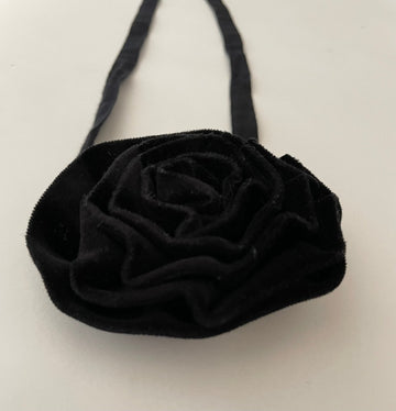 black velvet flower accessory with ties on a white background