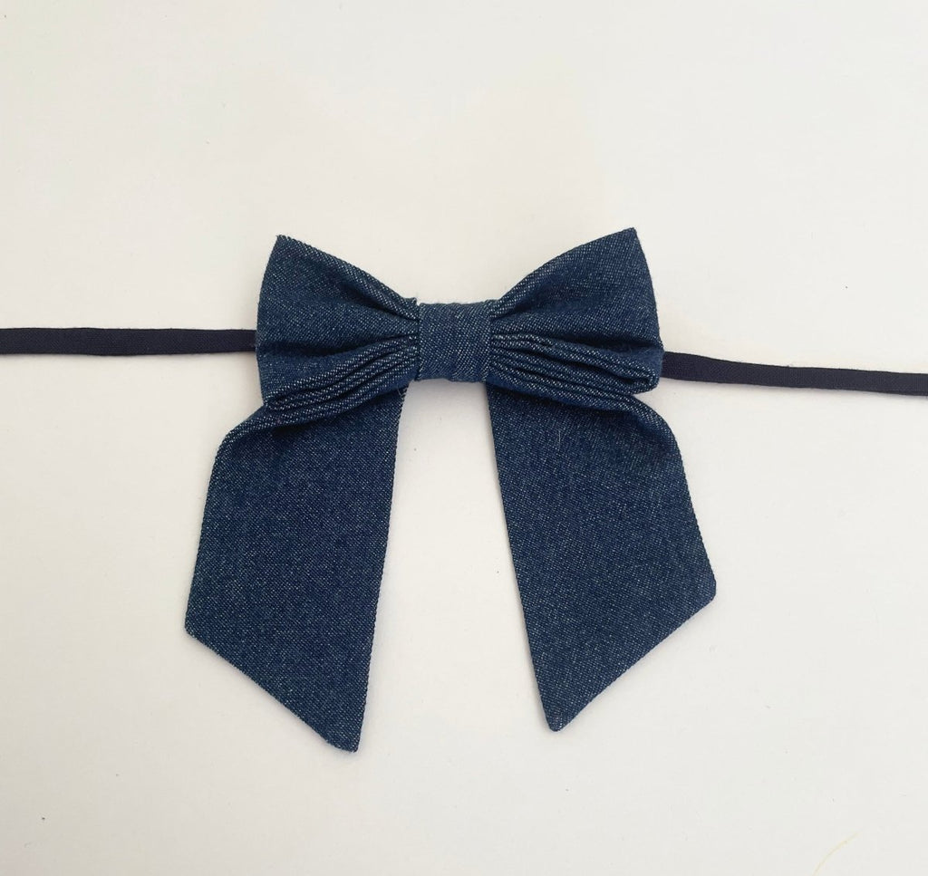 small sized denim bow accessory with fabric ties handmade from upcycled denim, displayed against a white background