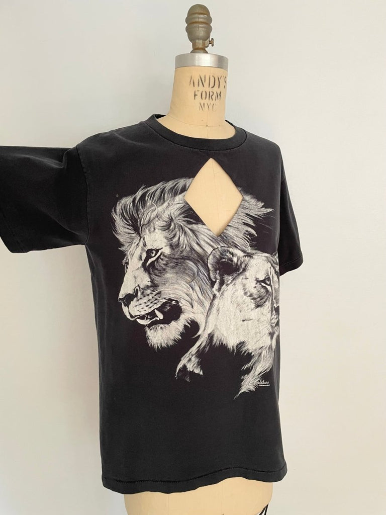 A black t-shirt with a diamond cut-out design featuring a lion and lioness print, displayed on a mannequin.