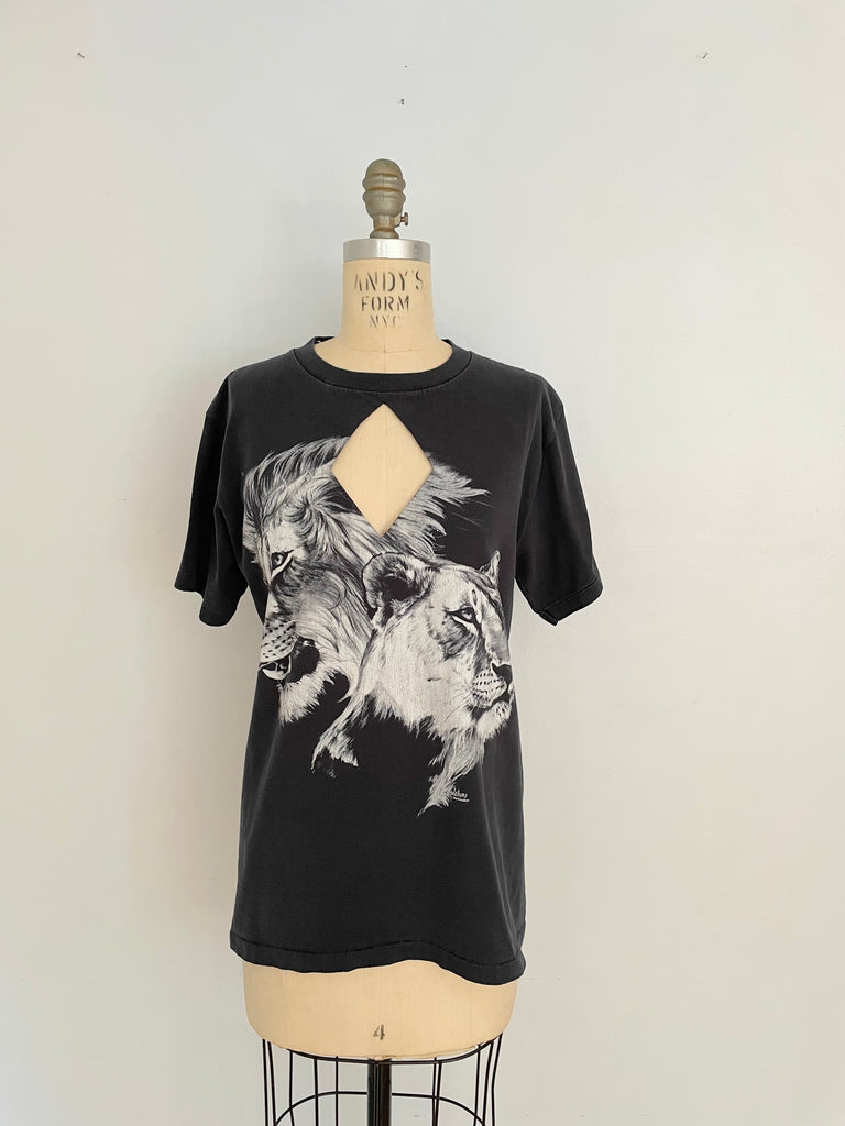 A black t-shirt with a diamond cut-out design featuring a lion and lioness print, displayed on a mannequin.