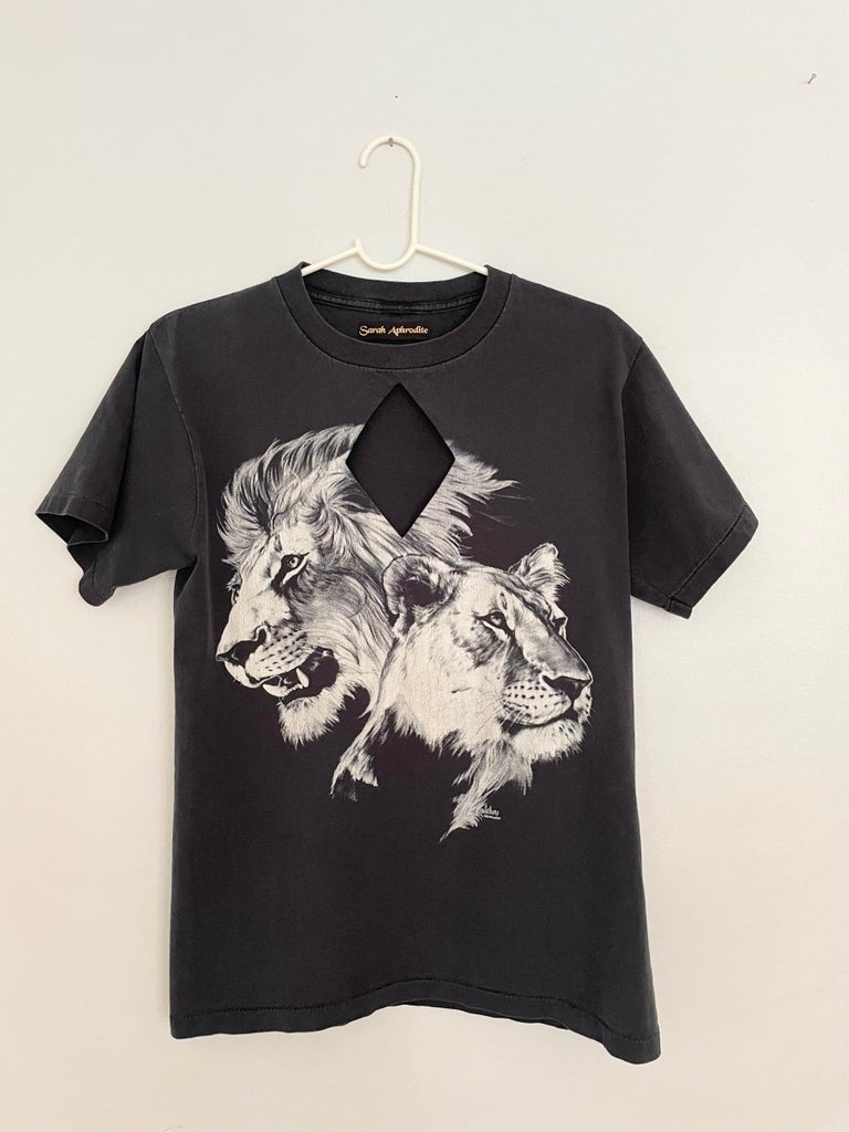 A black t-shirt with a diamond cut-out design featuring a lion and lioness print, displayed on a mannequin.