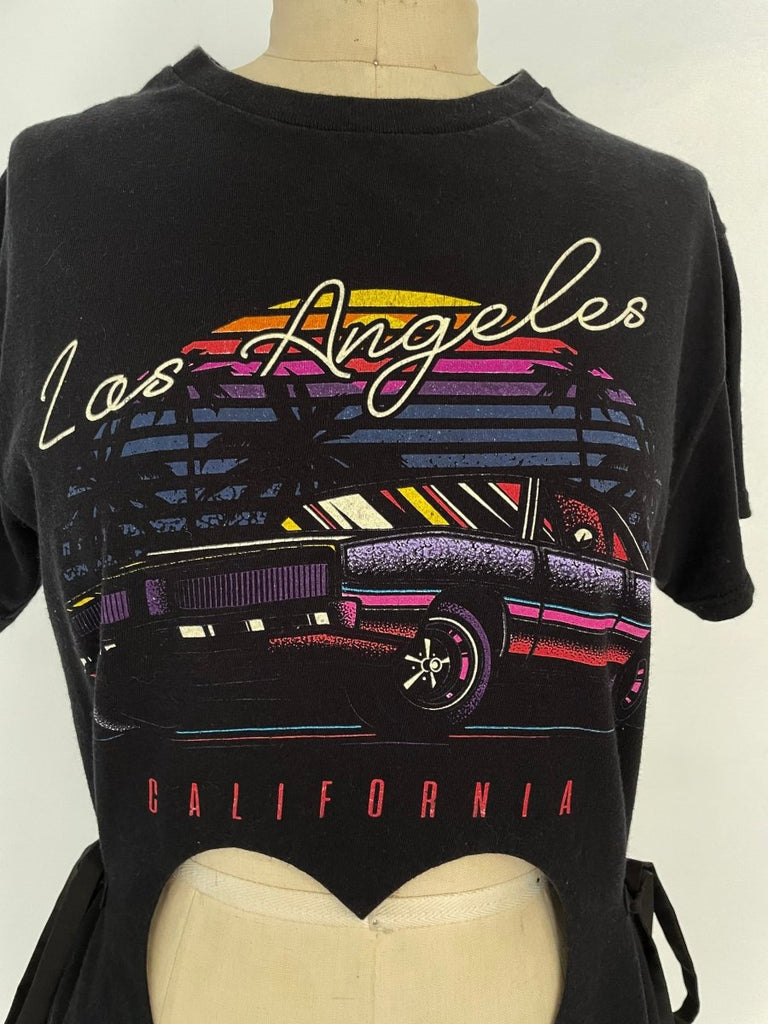 A mannequin displaying a Los Angeles print t-shirt with a double heart cut out at the front, tied at the waist. The shirt has a colorful design with a car and palm trees.