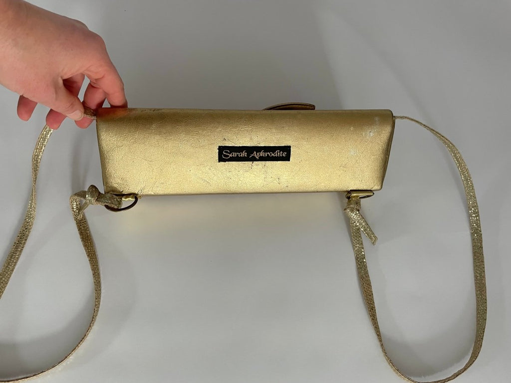back of a one-of-a-kind gold pleather archival top bag with a label on the back