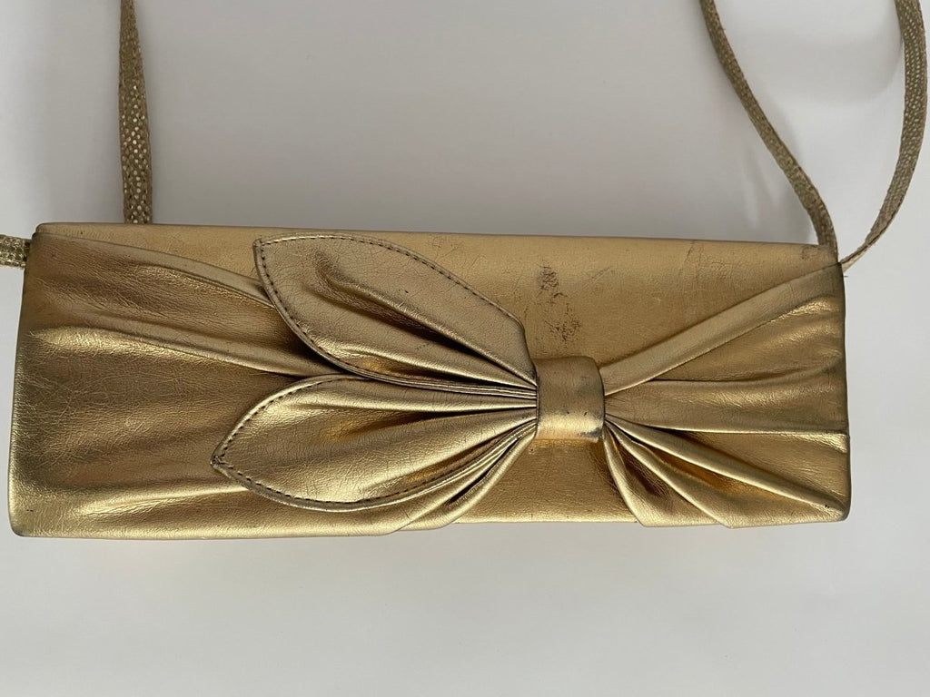 close up front view of one-of-a-kind gold pleather archival top bag with a bow on it