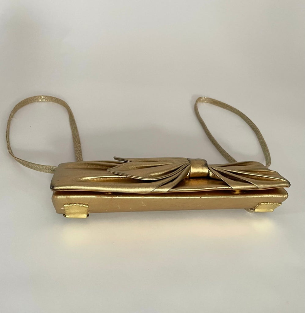 Front view of one-of-a-kind gold pleather archival top bag with a bow on it