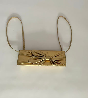 Front view of one-of-a-kind gold pleather archival top bag with a bow on it