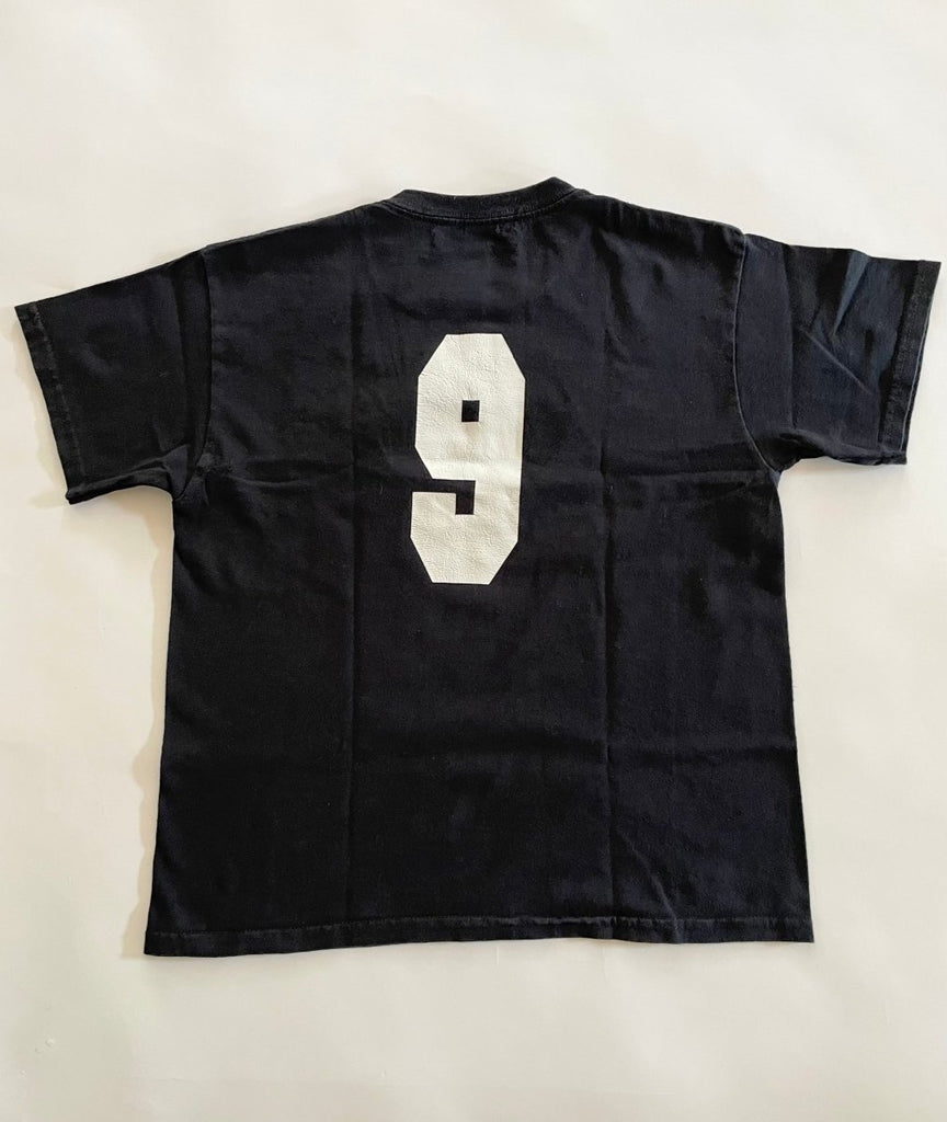back view of handmade heart cut-out t-shirt  with a varsity '9' on the back displayed on flat on the floor