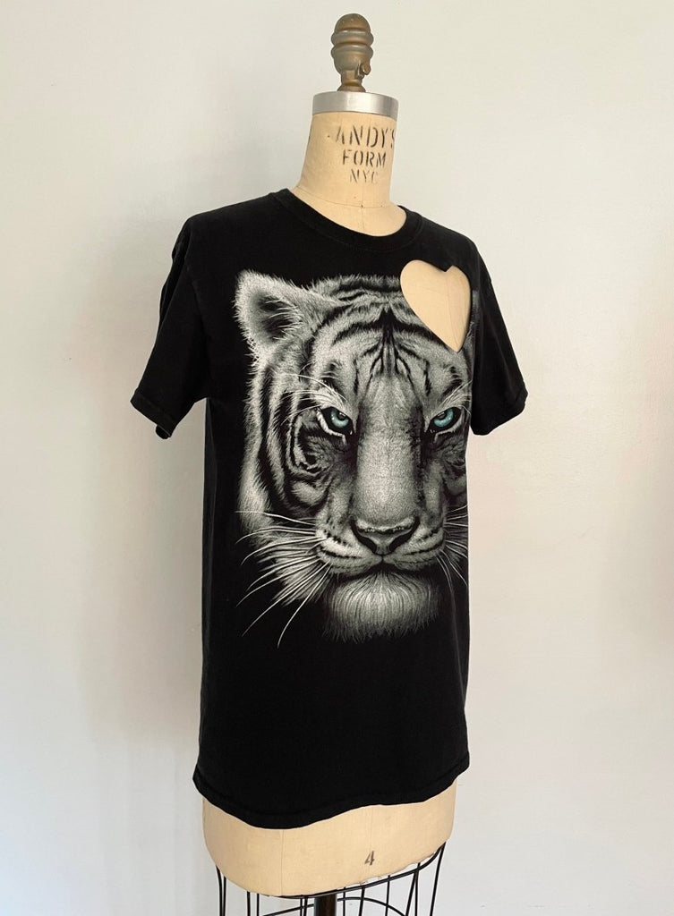 Black t-shirt with a graphic of a white tiger and a heart cut-out on the shoulder- displayed on a mannequin at a side angle