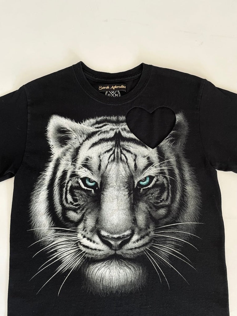 detail of black t-shirt with a graphic of a white tiger and a heart cut-out on the shoulder- made with a reused tshirt by Sarah Aphrodite-displayed flat on the floor