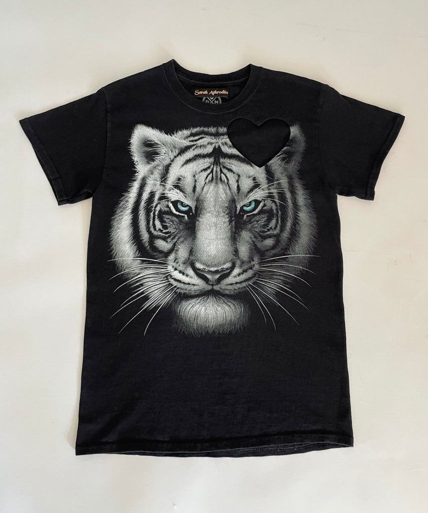 Black t-shirt with a graphic of a white tiger and a heart cut-out on the shoulder- displayed flat on the floor