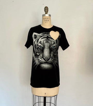 Black t-shirt with a graphic of a white tiger and a heart cut-out on the shoulder- displayed on a mannequin.