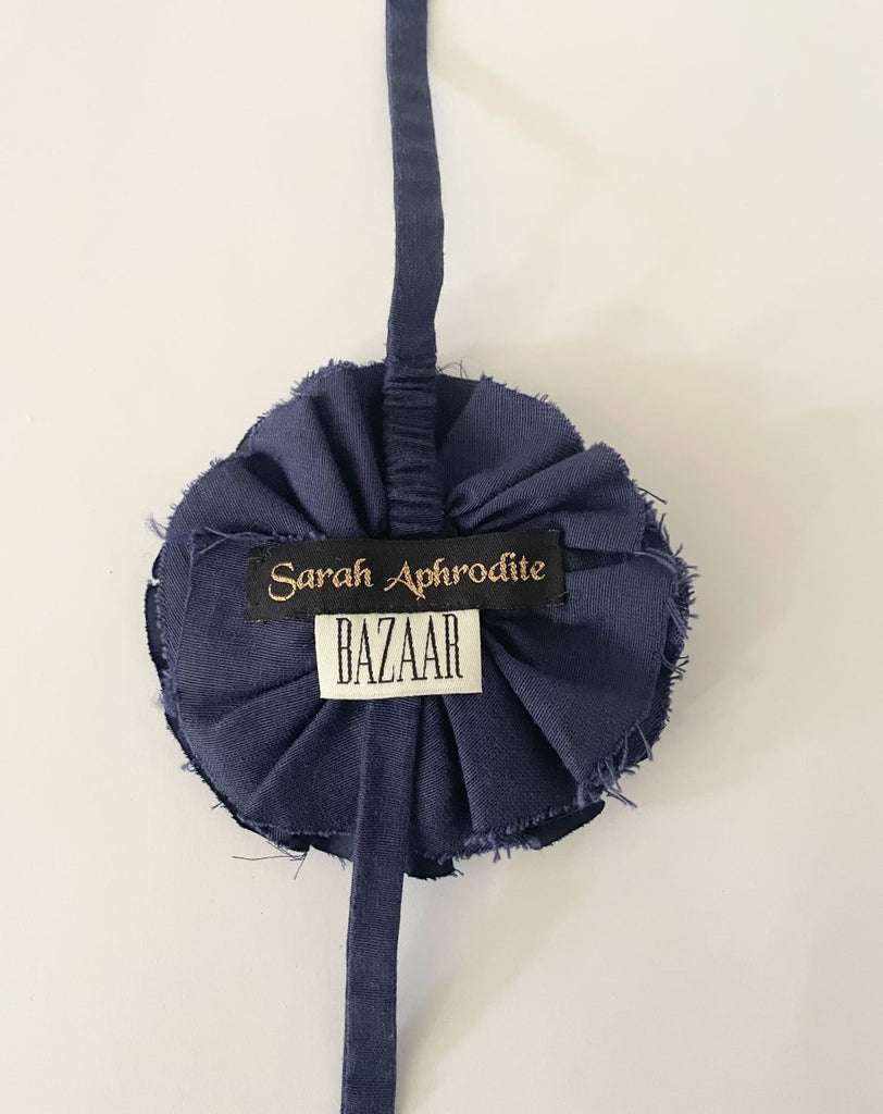 Handmade navy fabric flower accessory with ties and gold nautical button by Sarah Aphrodite. 5.5 inches wide.