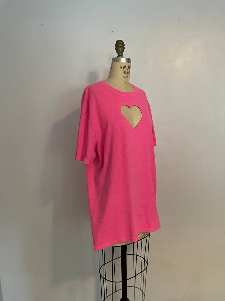 A bright pink t-shirt with a heart cut-out in the center, displayed on a mannequin.