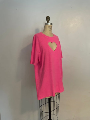A bright pink t-shirt with a heart cut-out in the center, displayed on a mannequin.