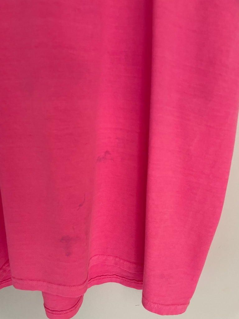 close up of a bright pink t-shirt with a stain  on the bottom of the shirt