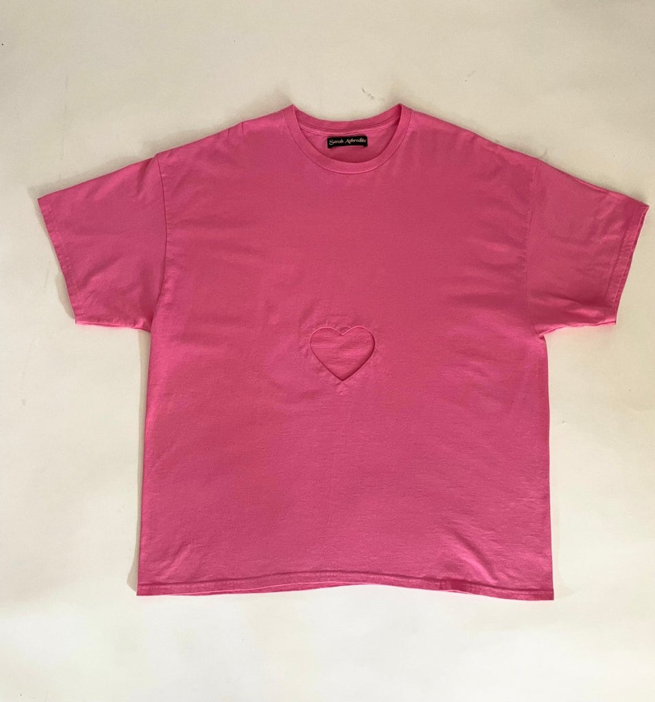 Oversized pink t-shirt with a heart cut-out in the center, displayed flat on the floor