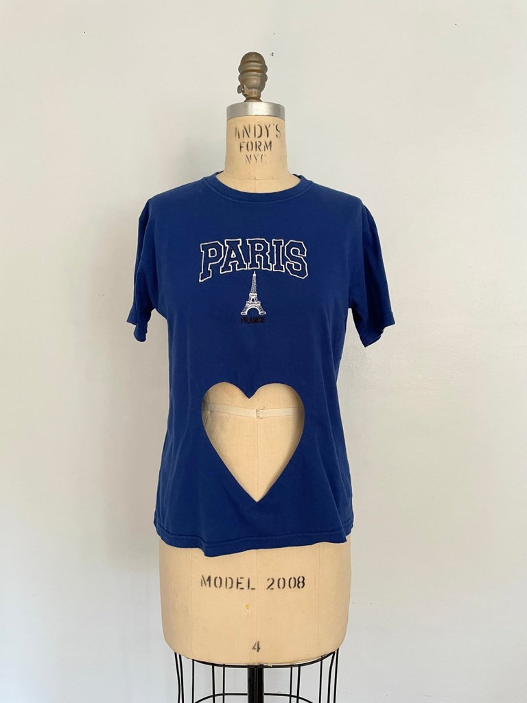 A royal blue t-shirt with a heart cut-out and 'Paris' text print, displayed on a mannequin with a size XS label.